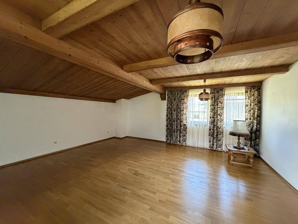 Geräumiger Dachbodenraum mit Holzdecke, sichtbaren Balken und Fenstern.