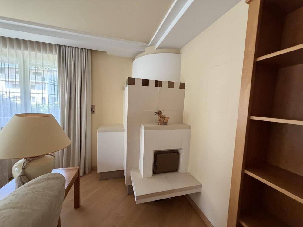 Helles Wohnzimmer mit modernem Kachelofen, Parkettboden und großen Fenstern.