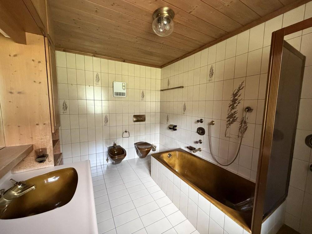 Badezimmer im Vintage-Stil mit Badewanne, Bidet, WC und braunen Armaturen.