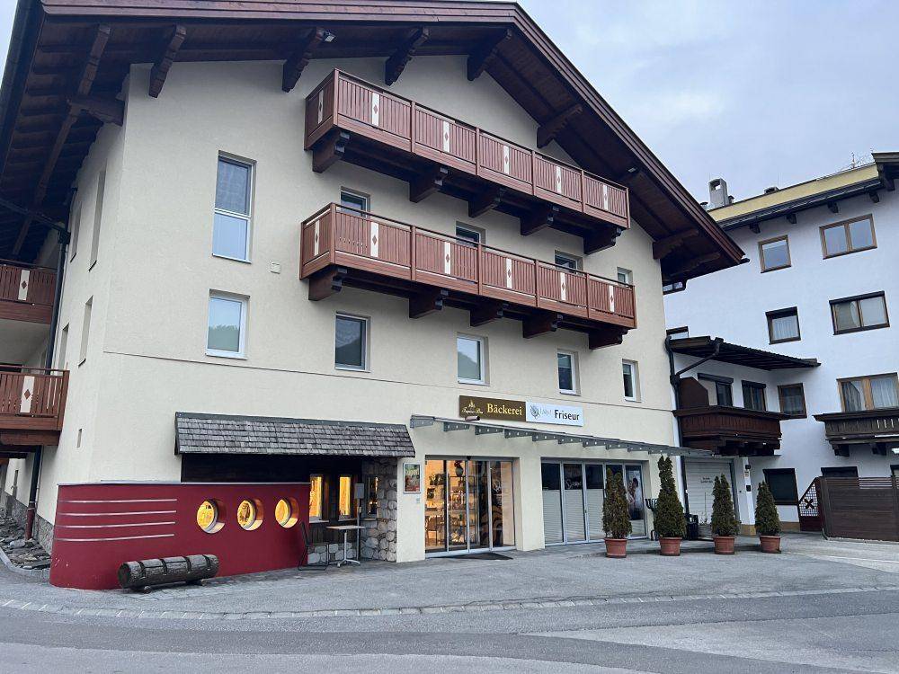 Traditionelles Gebäude mit Bäckerei und Friseur im Erdgeschoss sowie Holzbalkonen in den oberen Etagen.