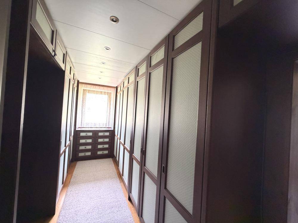 Geräumiger begehbarer Kleiderschrank mit vielen Einbauschränken und Fenster.