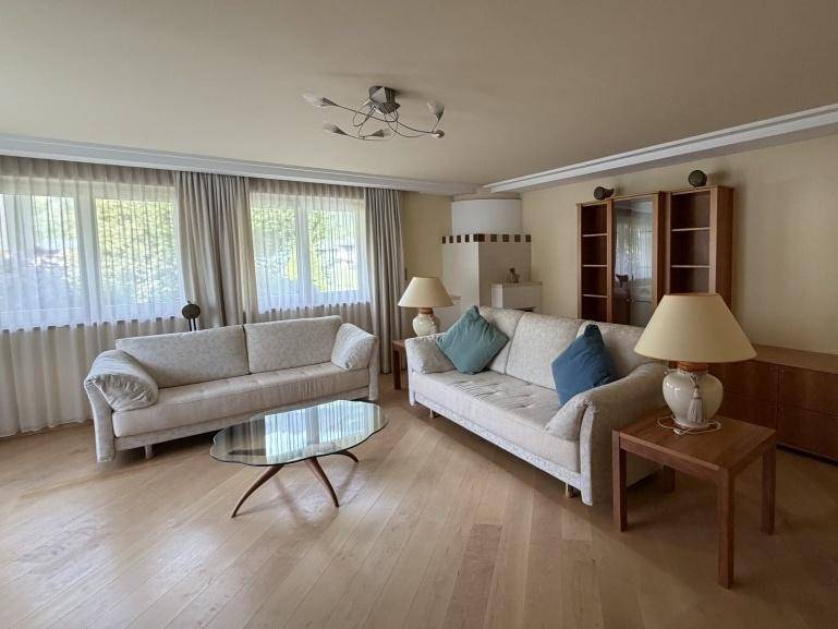 Geräumiges Wohnzimmer mit zwei Sofas, Couchtisch und hellem Kachelofen im Hintergrund.