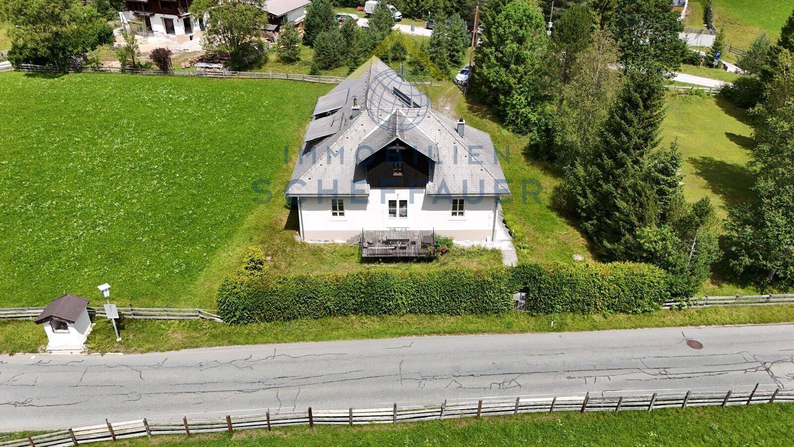 Hausfassade von vorne mit kleiner Terrasse und Blick auf die ländliche Umgebung.