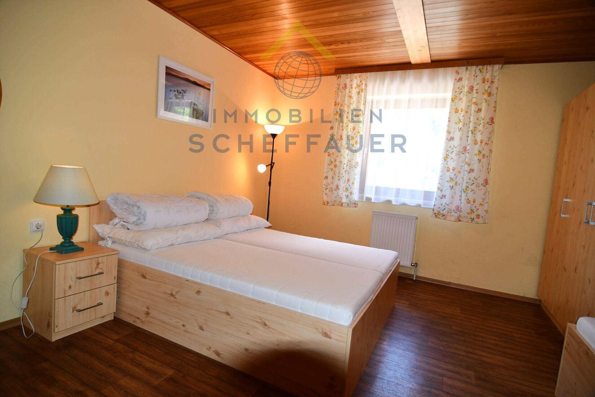 Gemütliches Schlafzimmer im Landhausstil mit Holzboden, Holzdecke und einem Doppelbett.