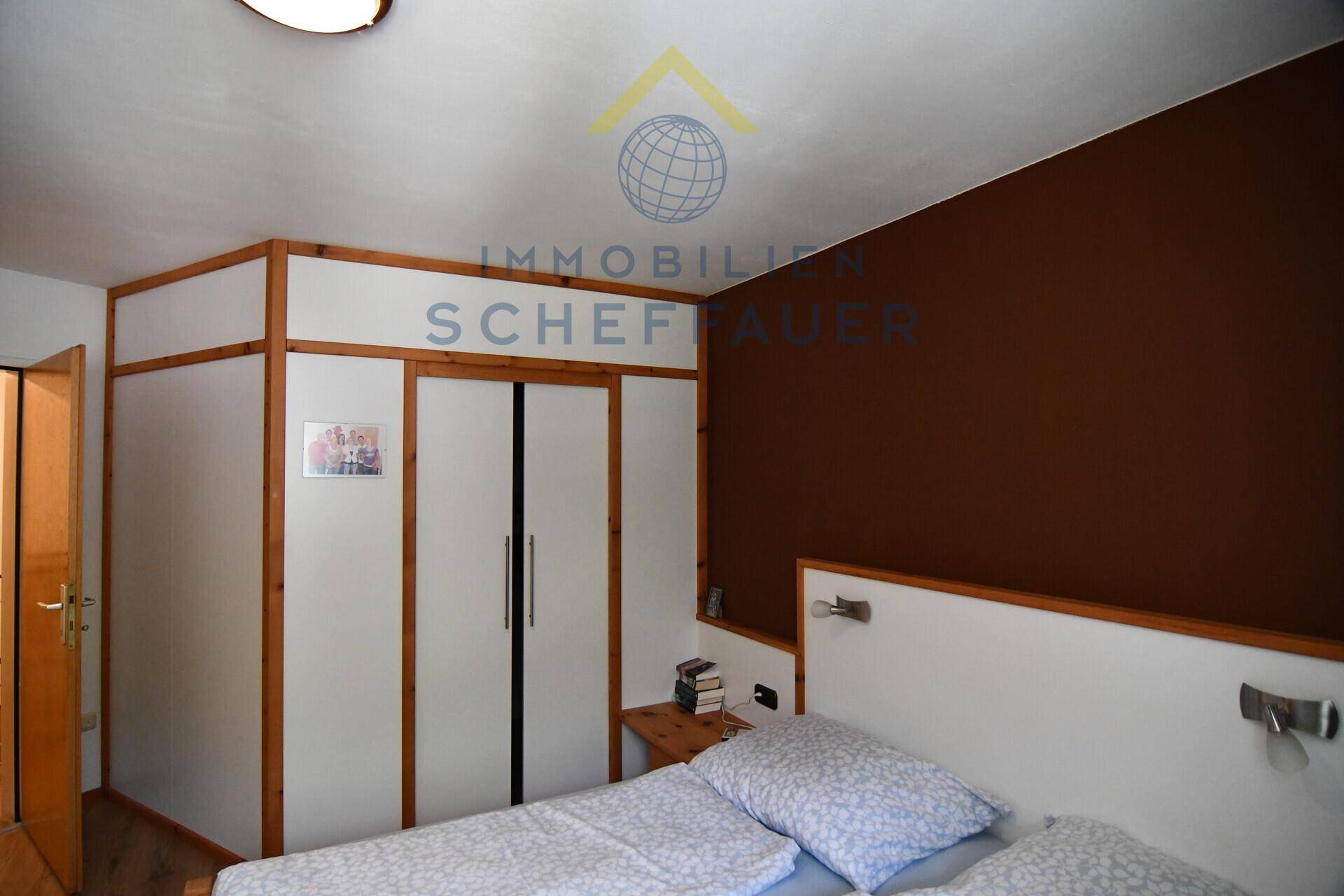 Schlafzimmer mit Doppelbett, integrierten Einbauschränken und brauner Akzentwand.