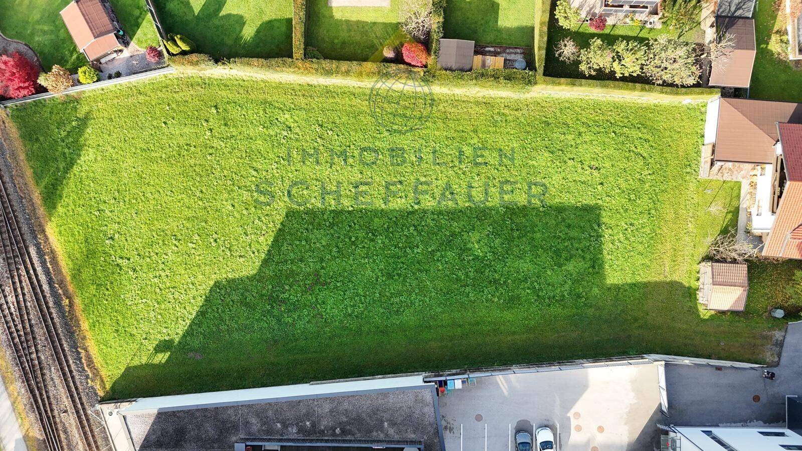 Draufsicht auf ein großes, rechteckiges Wiesengrundstück mit umliegender Bebauung.