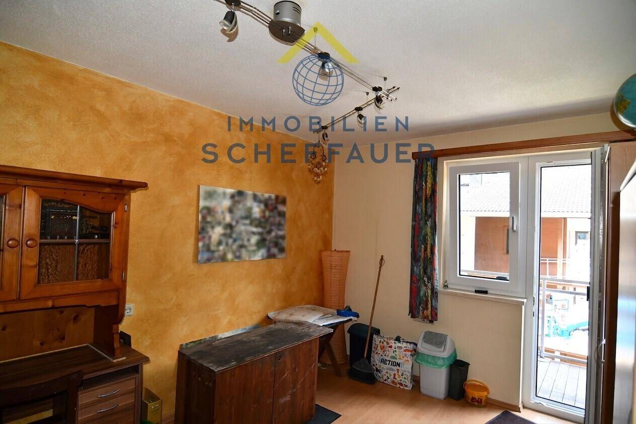 Innenraum mit gelb-orangefarbener Wandgestaltung und Zugang zu einem Balkon.