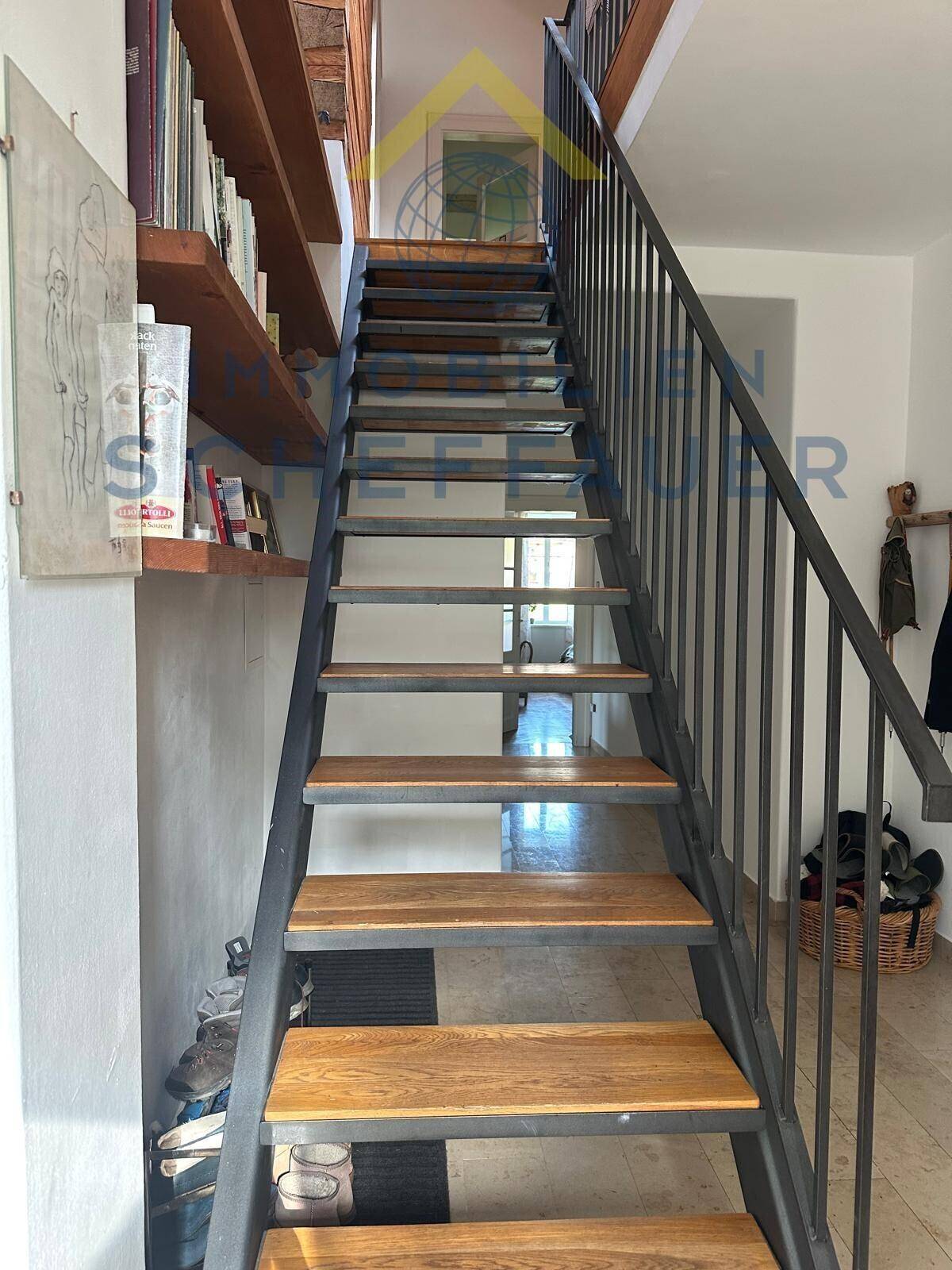 Moderne Holztreppe mit Metallgeländer verbindet die Etagen und bietet Stauraum unter den Stufen.