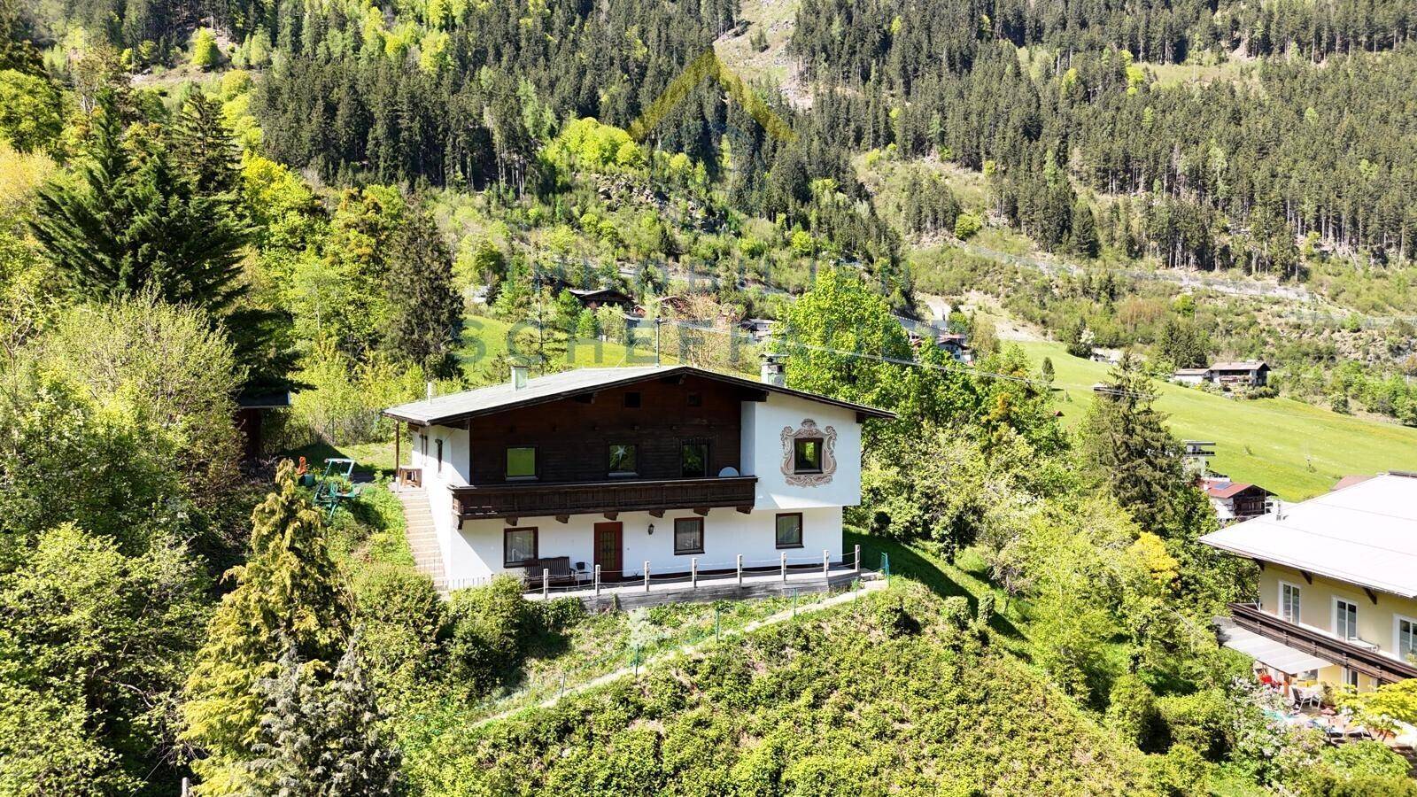 Alpines Wohnhaus mit traditioneller Fassadenmalerei und Holzelementen, umgeben von üppiger Natur.