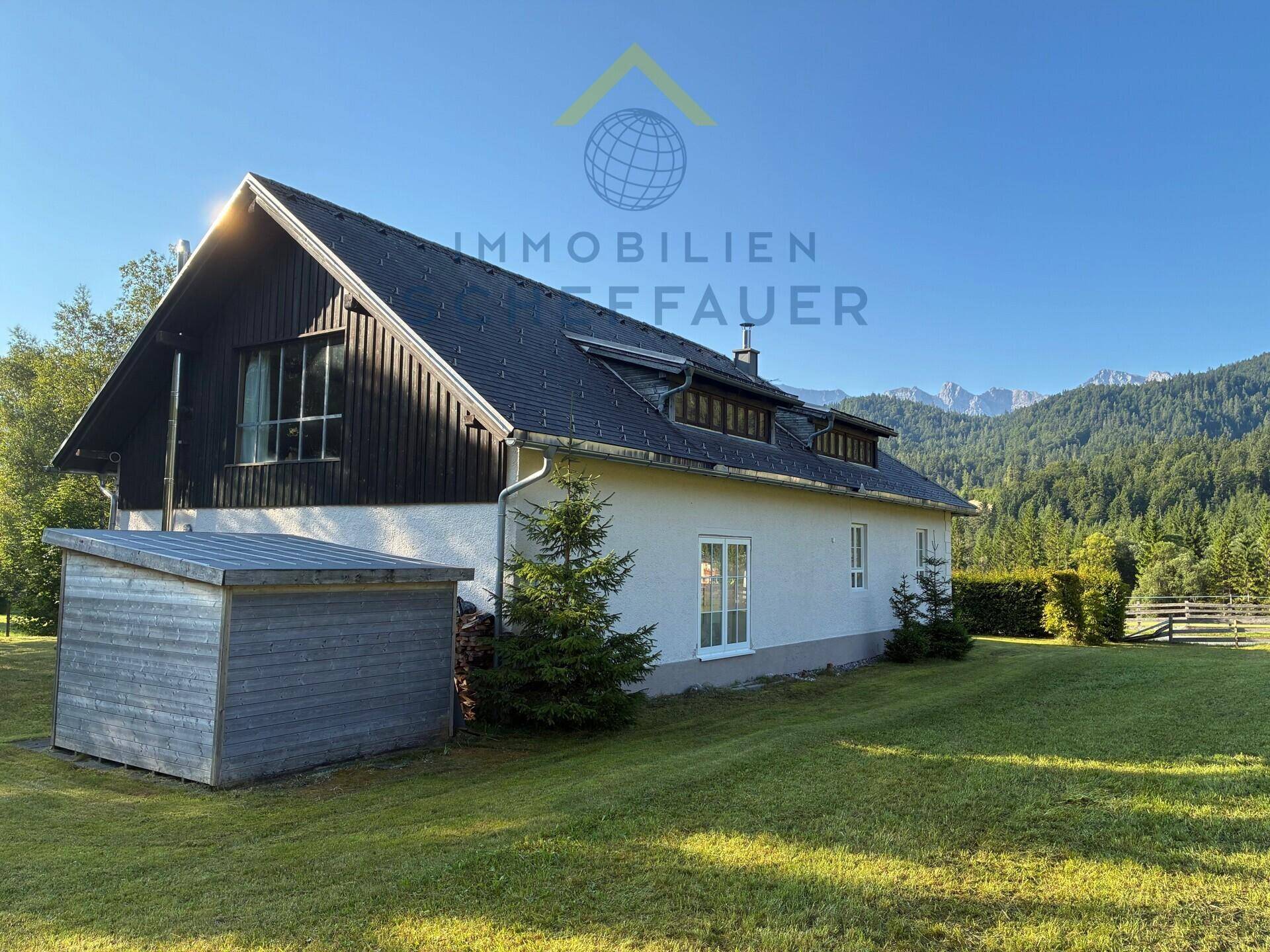 Rückansicht des Hauses mit großem Garten, Holzschuppen und Blick auf die Berge.