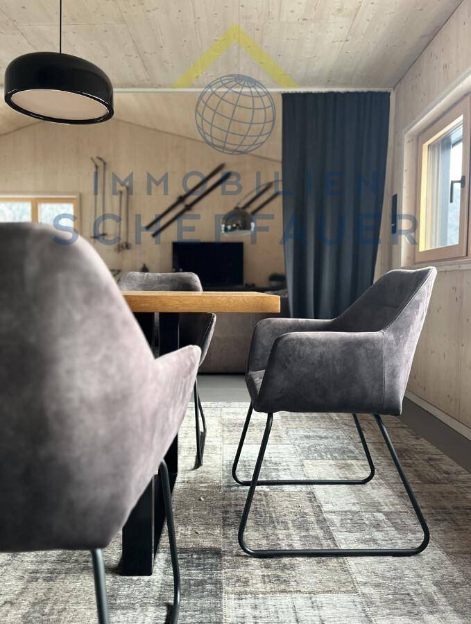 Essbereich mit modernen Stühlen, Holzwänden und Blick auf den angrenzenden Wohnbereich.