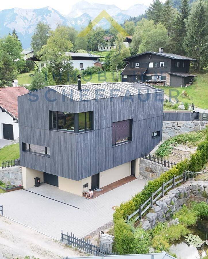 Zeitgenössisches Holzhaus mit moderner Architektur und integriertem Untergeschoss in alpiner Umgebung.