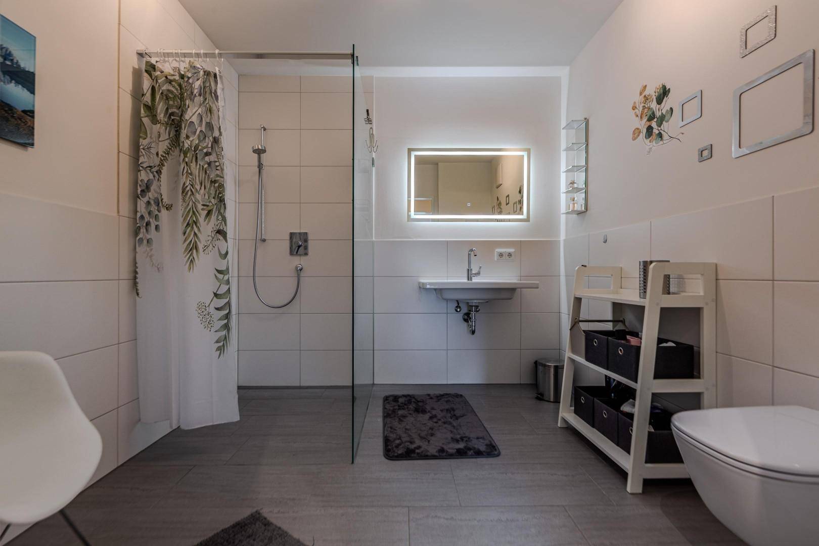 Modernes Badezimmer mit ebenerdiger Dusche, Einzelwaschbecken und Wand-WC.