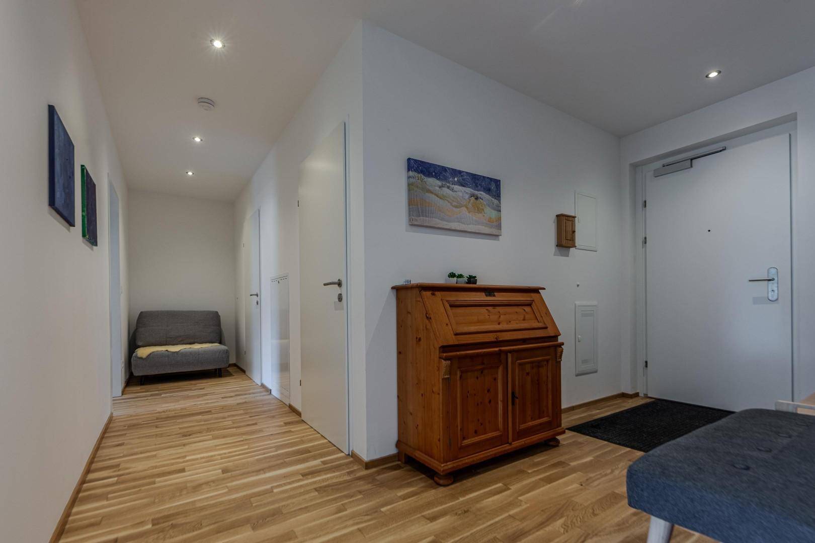 Heller Flur mit Holzboden und einem traditionellen Holzschrank als Blickfang.
