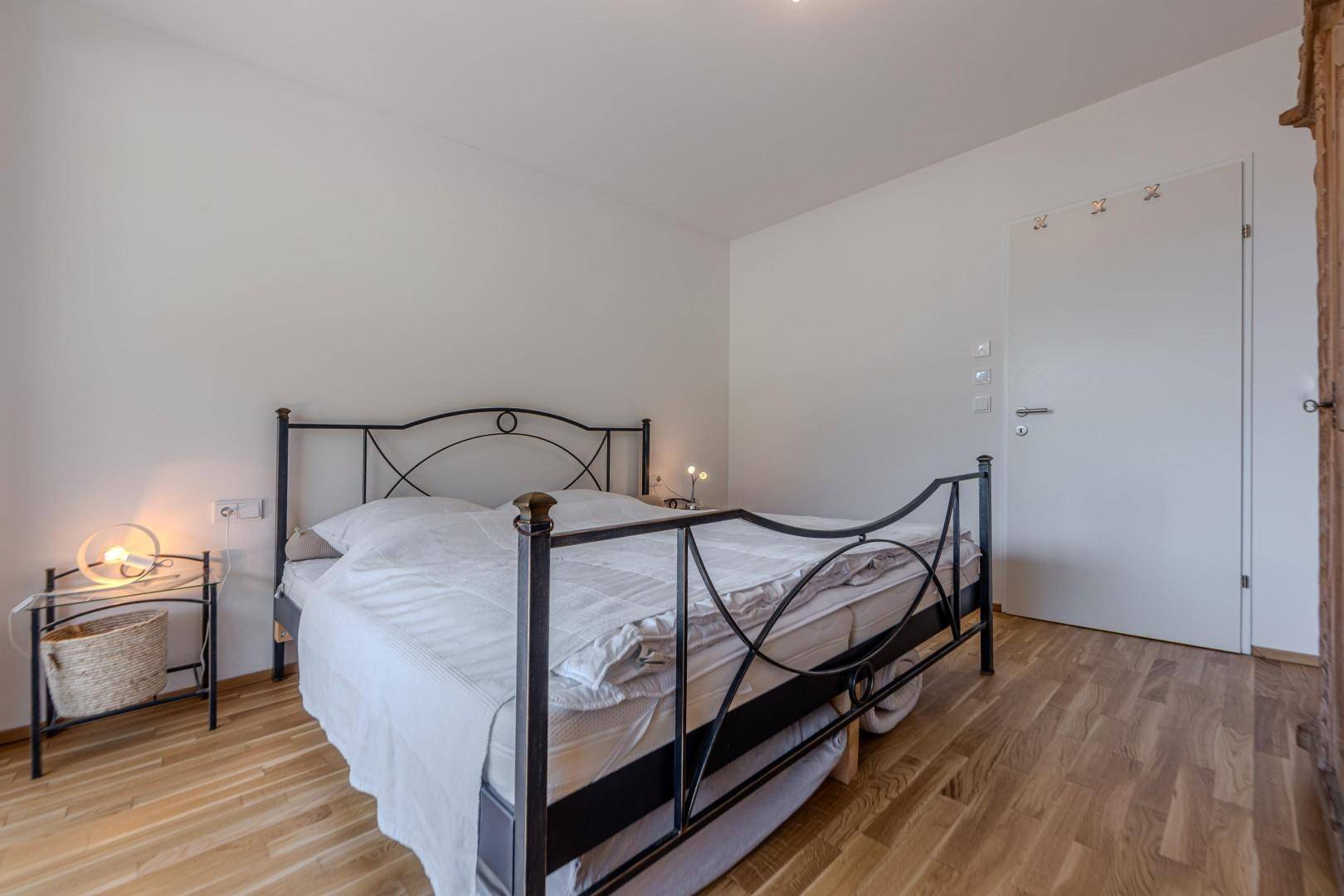 Helles Schlafzimmer mit Doppelbett und warmem Holzboden.