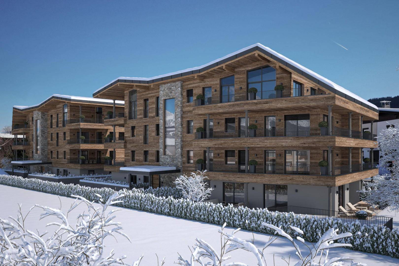 Neubau mit eleganter Holz- und Steinfassade, großzügigen Balkonen und winterlicher Umgebung.