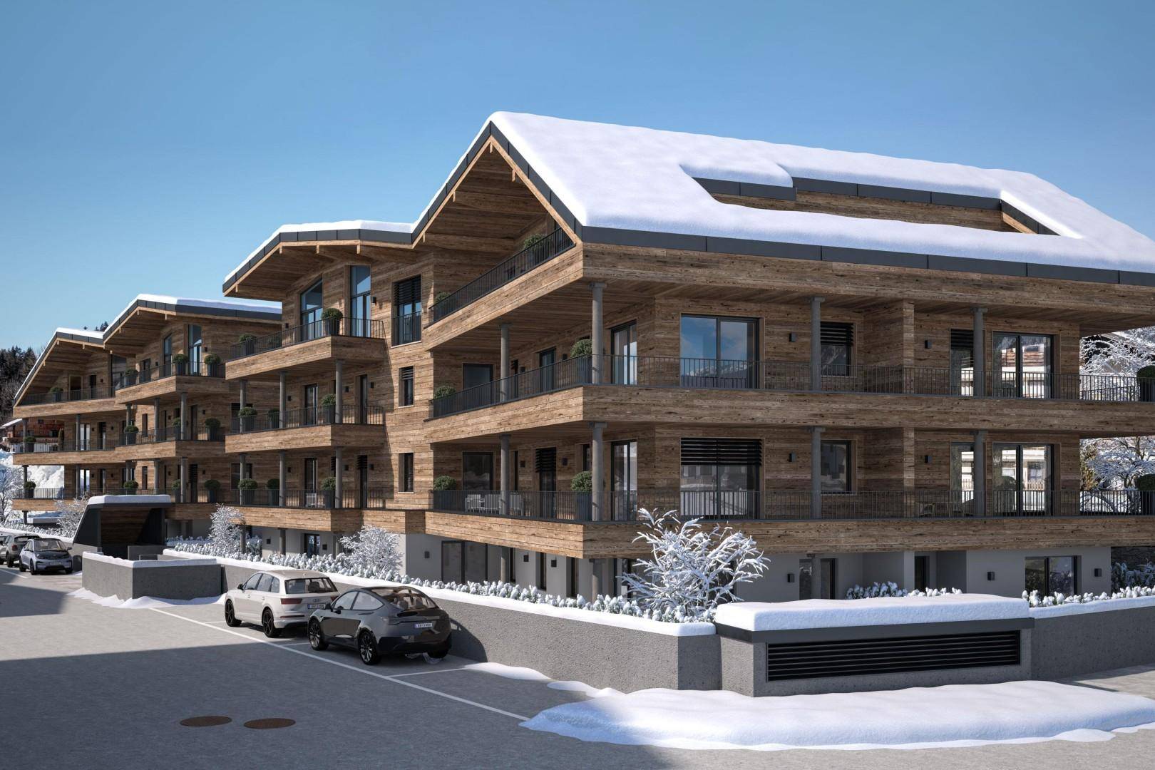 Neubau im Chalet-Stil mit Holzfassade und großzügigen Balkonen, eingebettet in eine winterliche Berglandschaft.