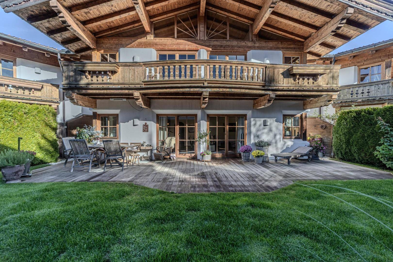 Große Holzterrasse mit Gartenmöbeln und Zugang zum gepflegten Rasenbereich vor dem Chalet.