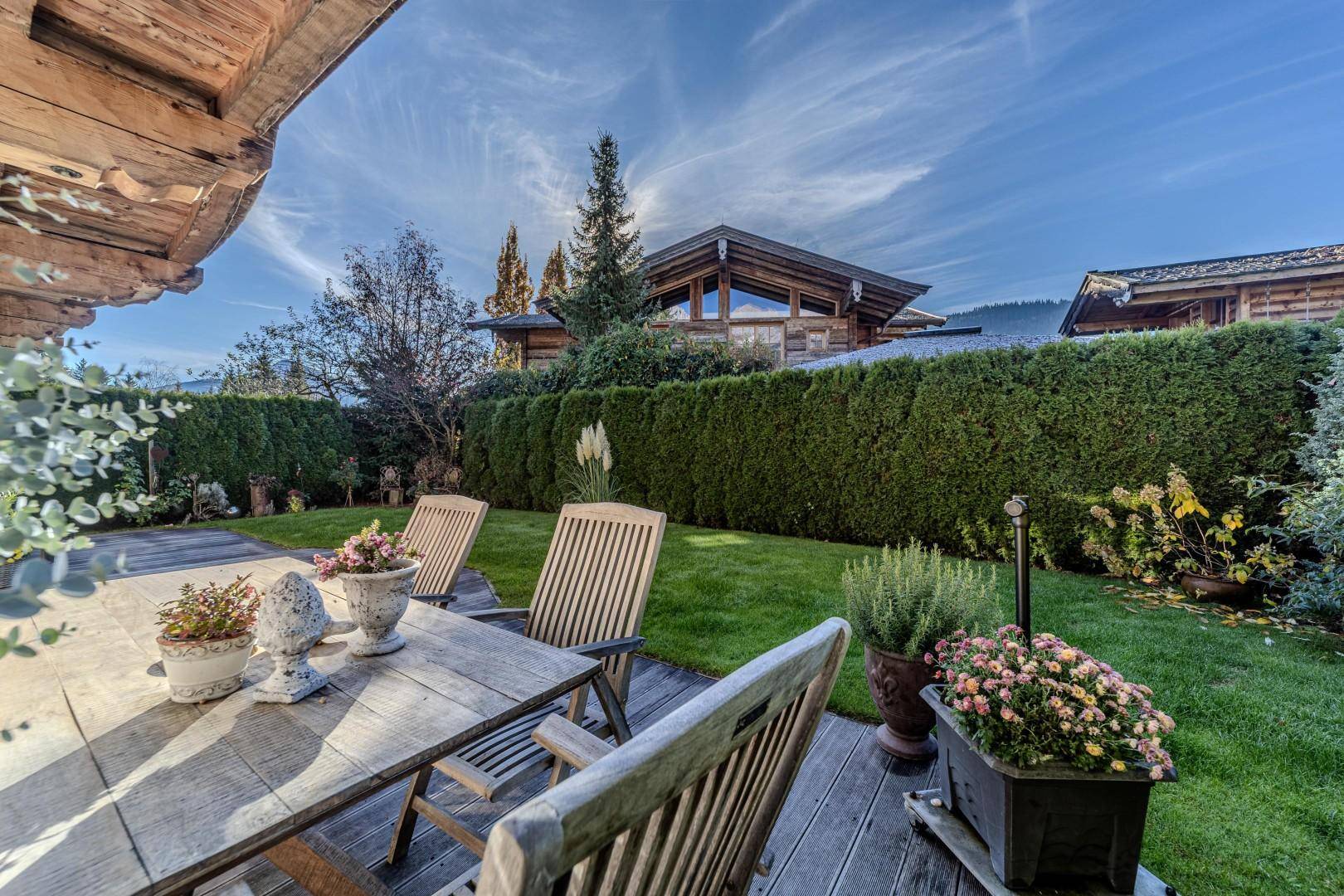 Gemütliche Holzterrasse mit Gartenmöbeln und Blick über den gepflegten Rasen und die Hecke.