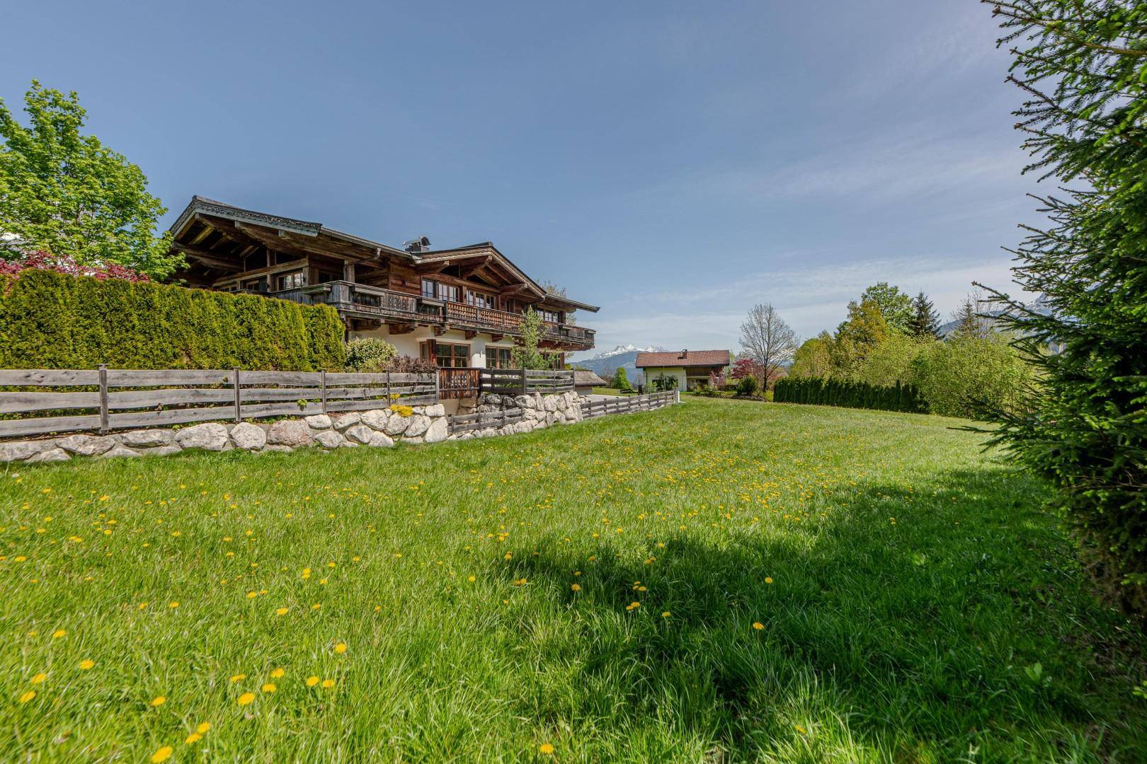 Großes Holzhaus im Chalet-Stil mit einem gepflegten Garten und Blick auf die umliegende Natur.