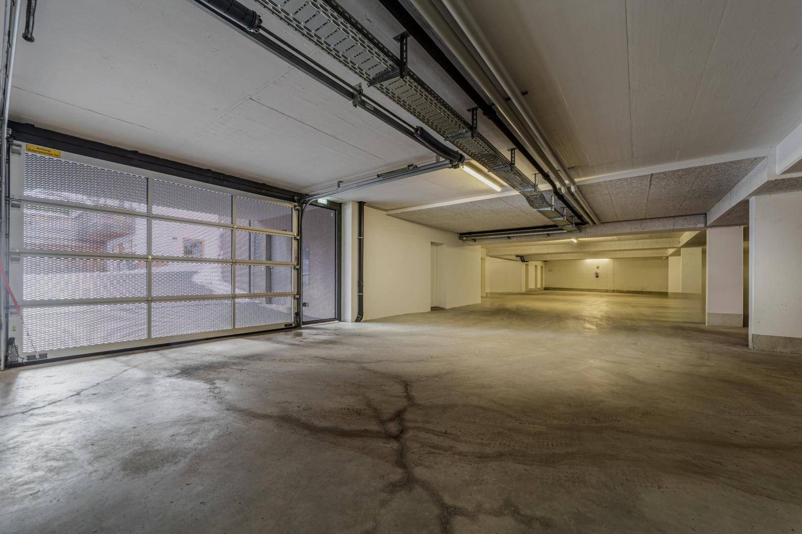 Geräumige Tiefgarage mit Betonboden und Rolltor, bietet viel Platz für Fahrzeuge.