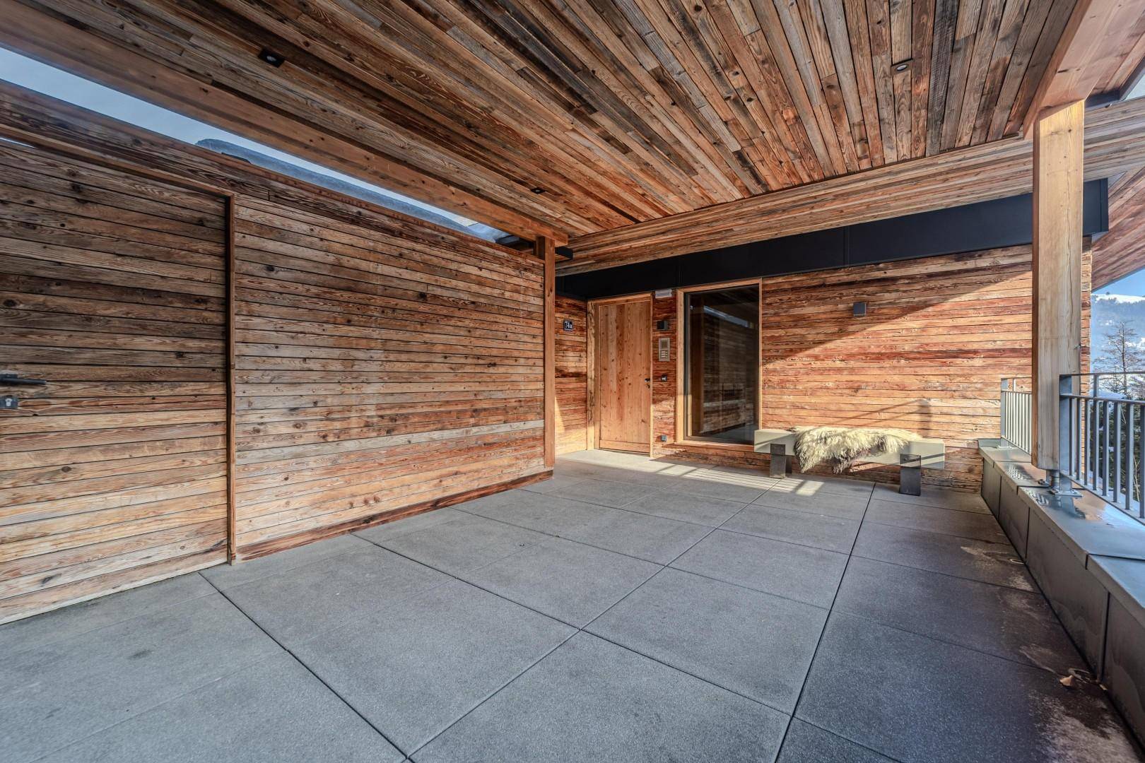 Überdachte Terrasse mit Holzwänden und Steinboden, ideal für entspannte Stunden im Freien.