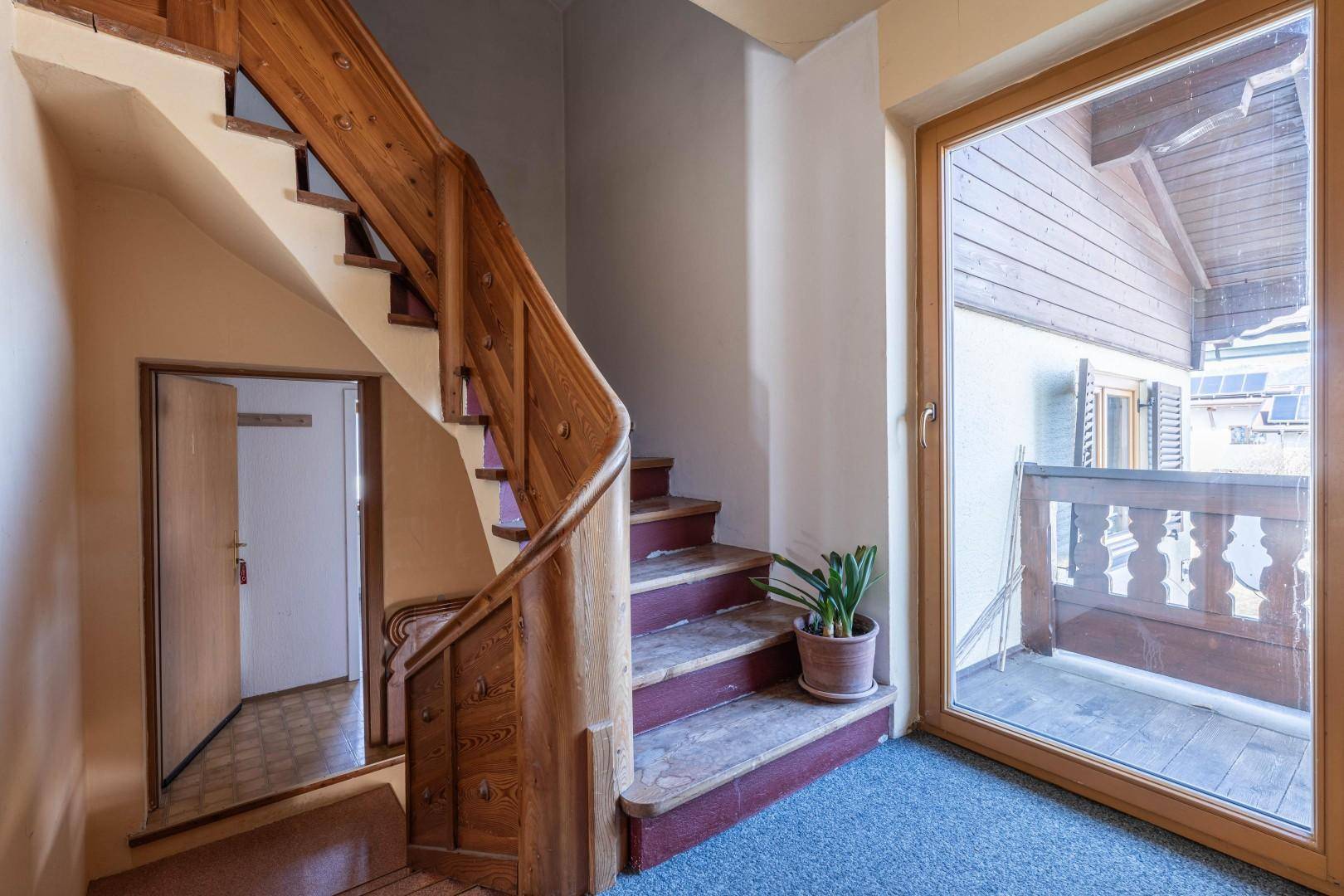 Eingangsbereich mit Holztreppe und Teppichboden, führt zu den oberen Etagen des Hauses.