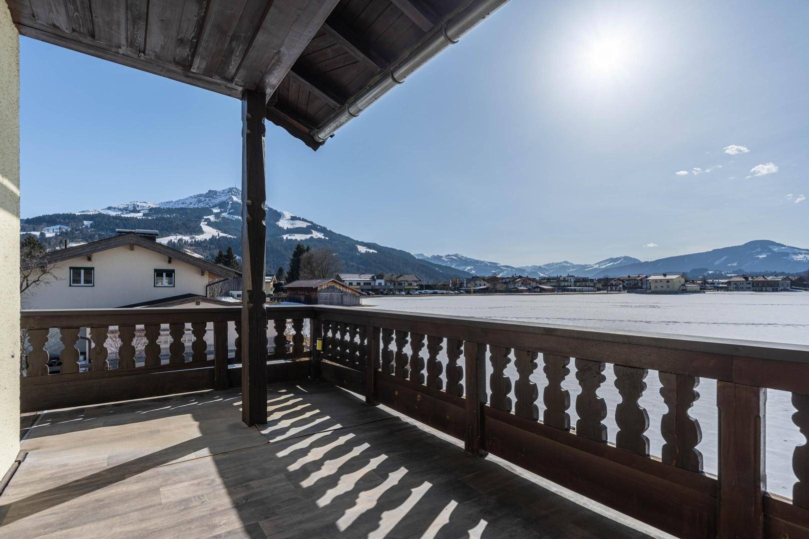 Geräumiger Holzbalkon mit traditionellem Geländer und weitem Blick auf die verschneite Berglandschaft.