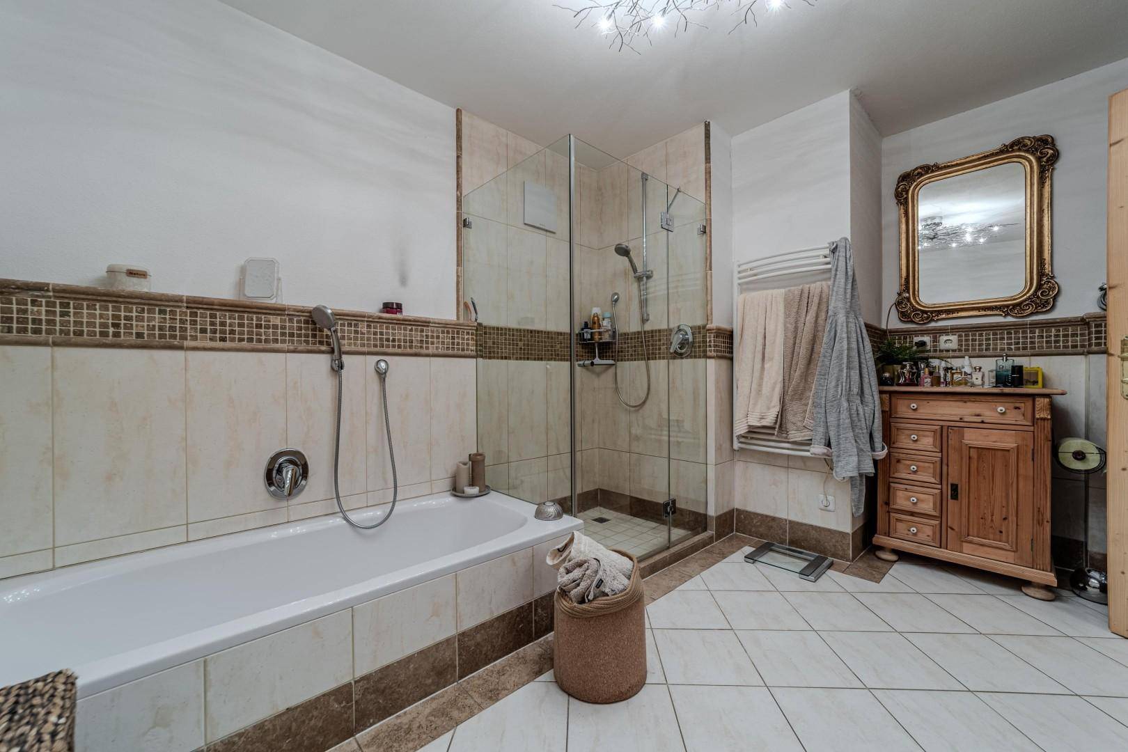 Helles Badezimmer mit Badewanne, Duschkabine und beheiztem Handtuchhalter.