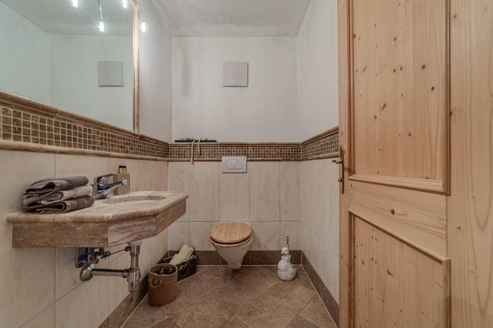 Gäste-WC mit Fliesenboden, Waschbecken und WC, in traditionellem Stil.