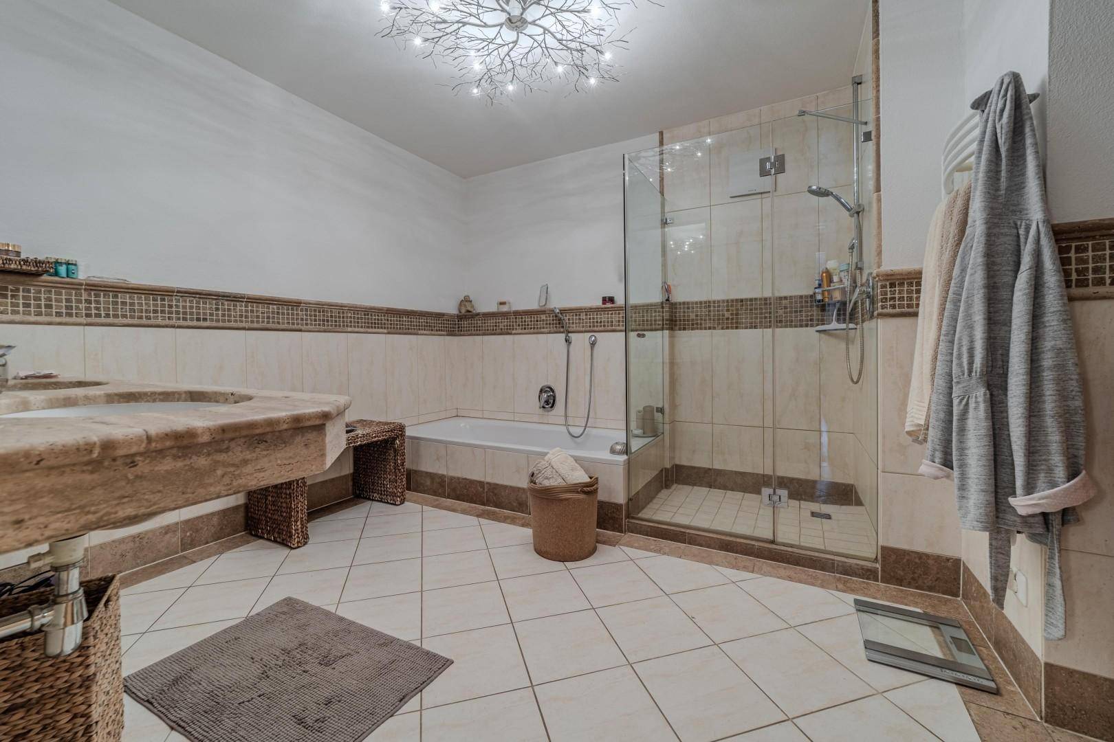 Geräumiges Badezimmer mit Badewanne, Dusche und Doppelwaschbecken in hellem Design.