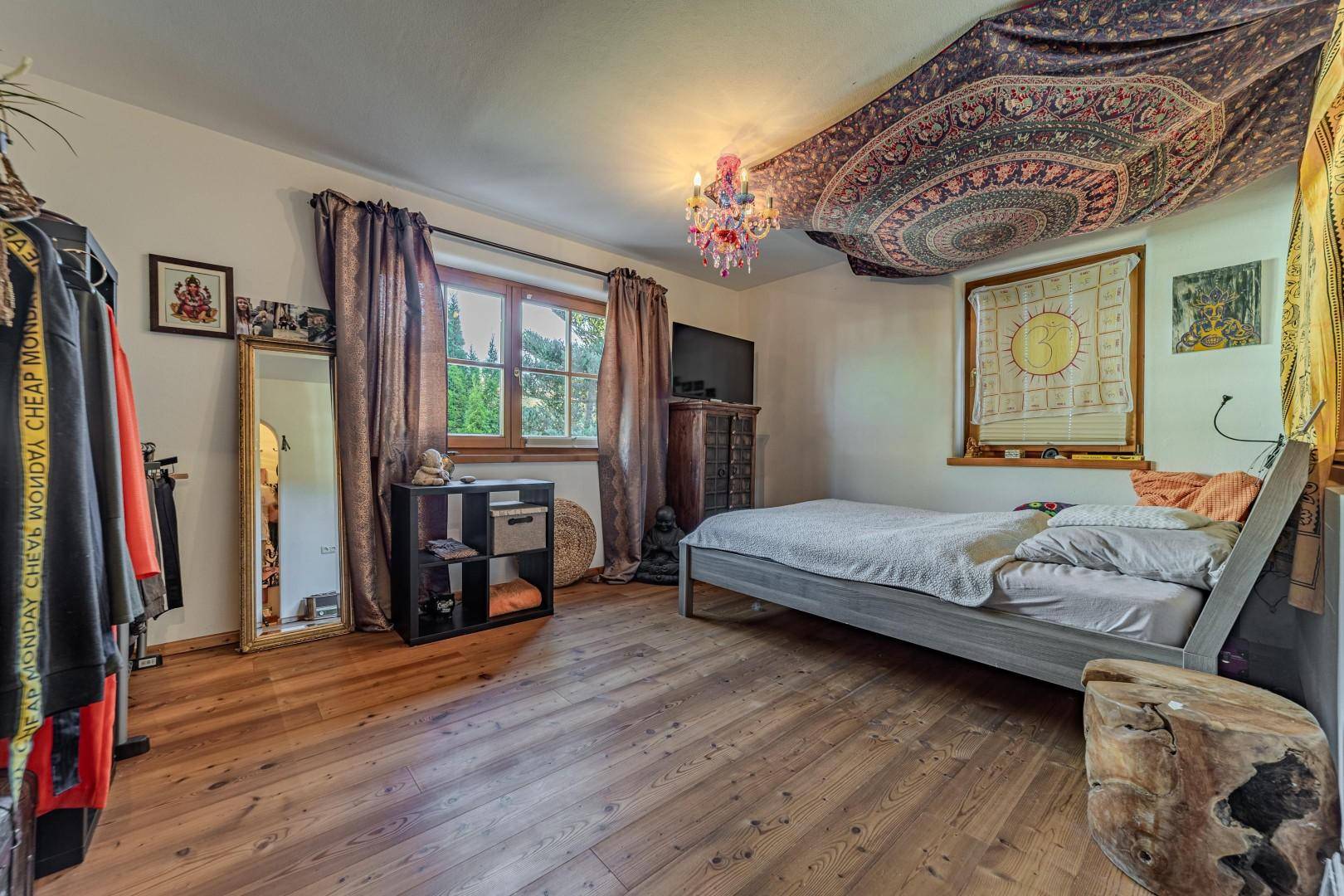 Individuell gestaltetes Schlafzimmer mit Holzboden und farbenfroher Dekoration.