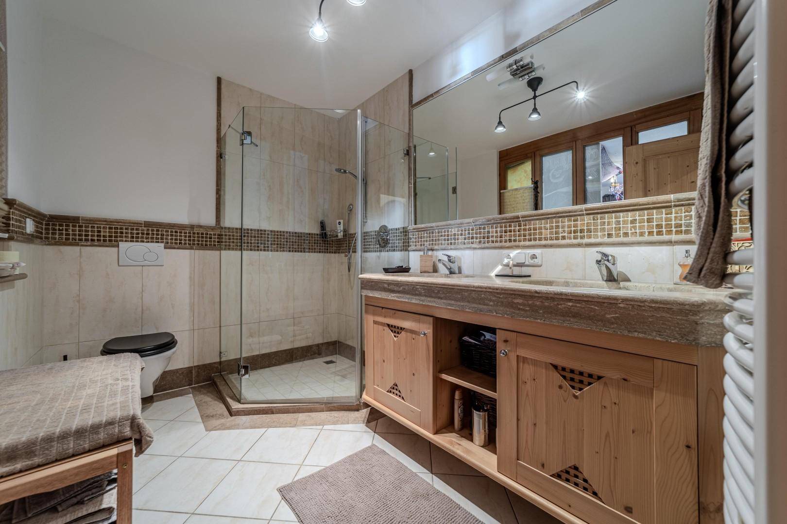 Modernes Badezimmer mit Dusche, Doppelwaschbecken und großem Spiegel.