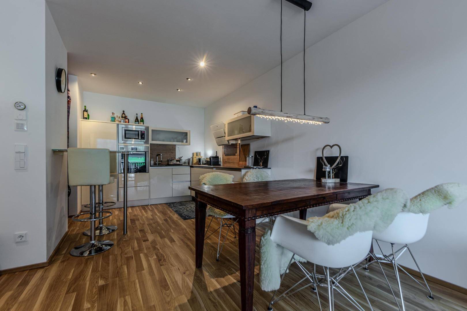 Moderne Einbauküche mit weißen Schränken, Holzboden und Essbereich.