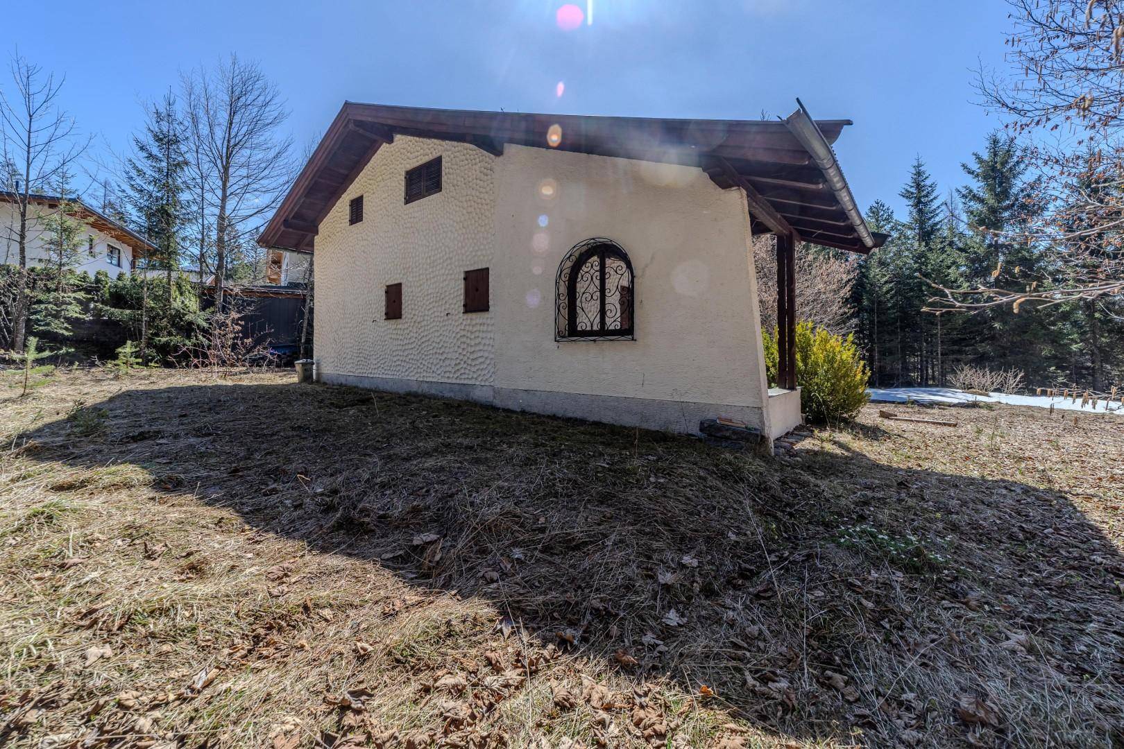 Rückseite des Hauses mit einem kleinen Fenster und Blick auf die umliegende Landschaft.