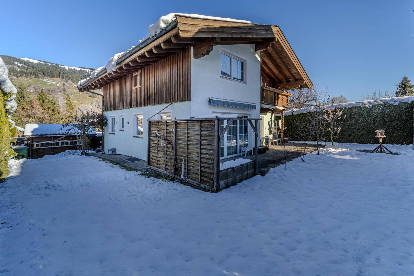 Gartenbereich im Winter mit Schnee, Terrasse und Blick auf die umliegende Landschaft.