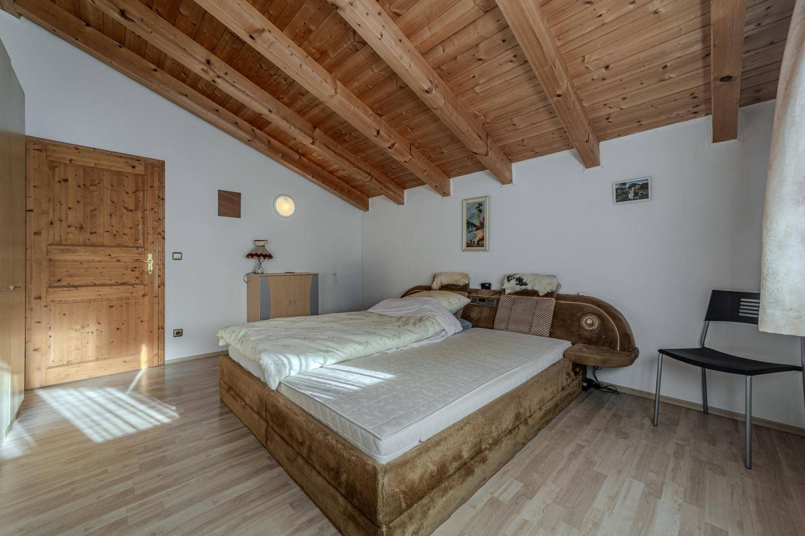 Helles Schlafzimmer mit sichtbaren Holzbalken und traditioneller Einrichtung.
