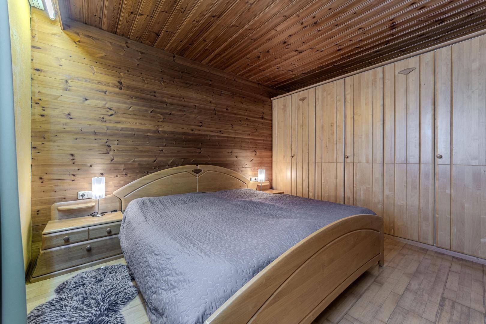 Schlafzimmer mit Holzvertäfelung, Holzboden und integriertem Kleiderschrank.