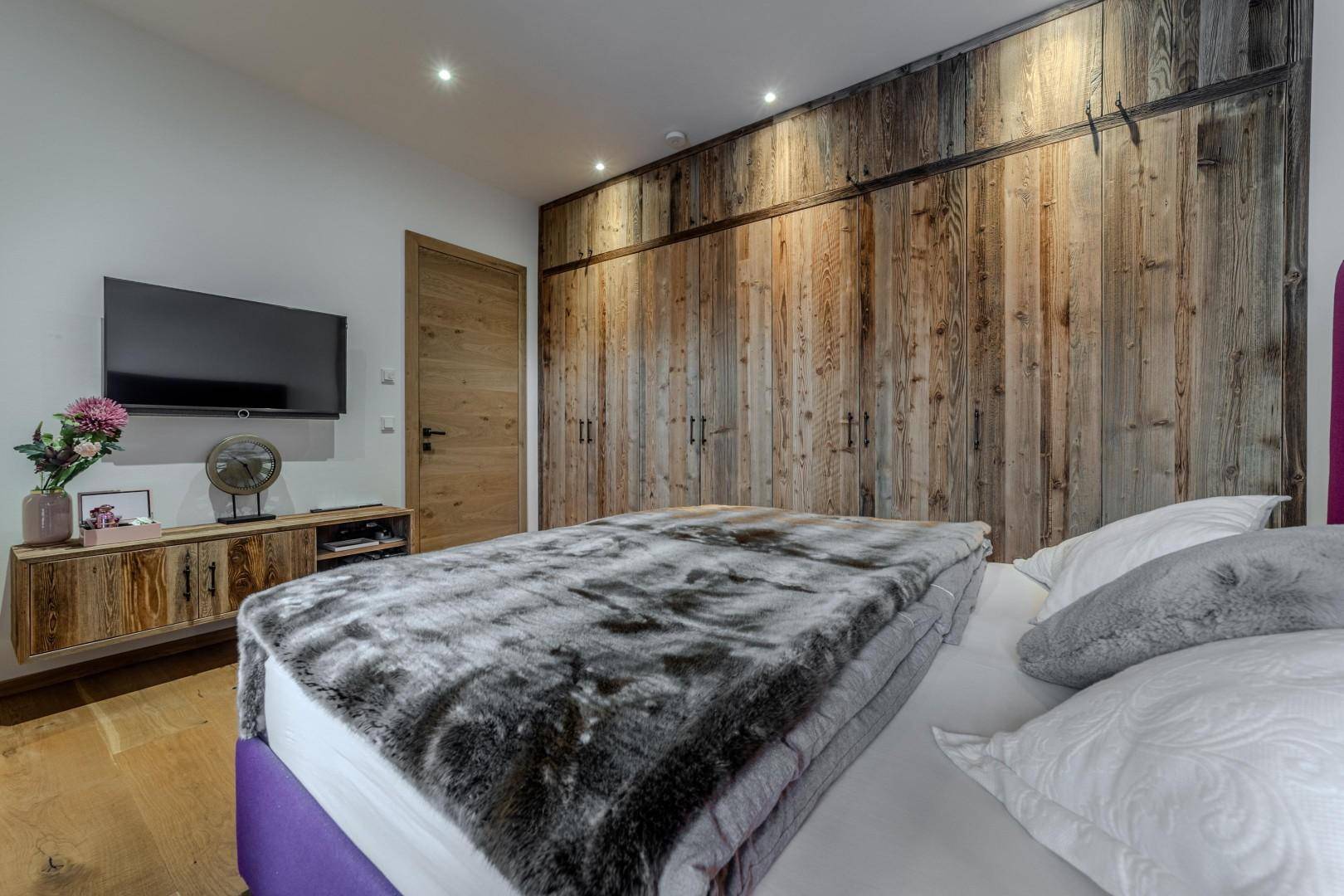 Schlafzimmer mit Holzeinbauschränken, großem Bett und modernem Design.