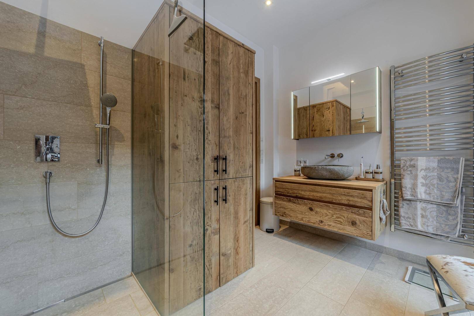 Modernes Badezimmer mit begehbarer Dusche, Holzwaschtisch und beheiztem Handtuchhalter.