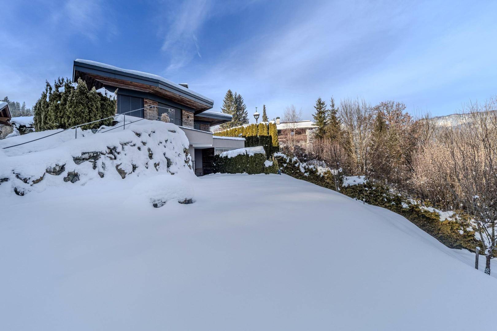 Außenansicht des modernen Gebäudes in verschneiter Berglandschaft mit viel Grün.