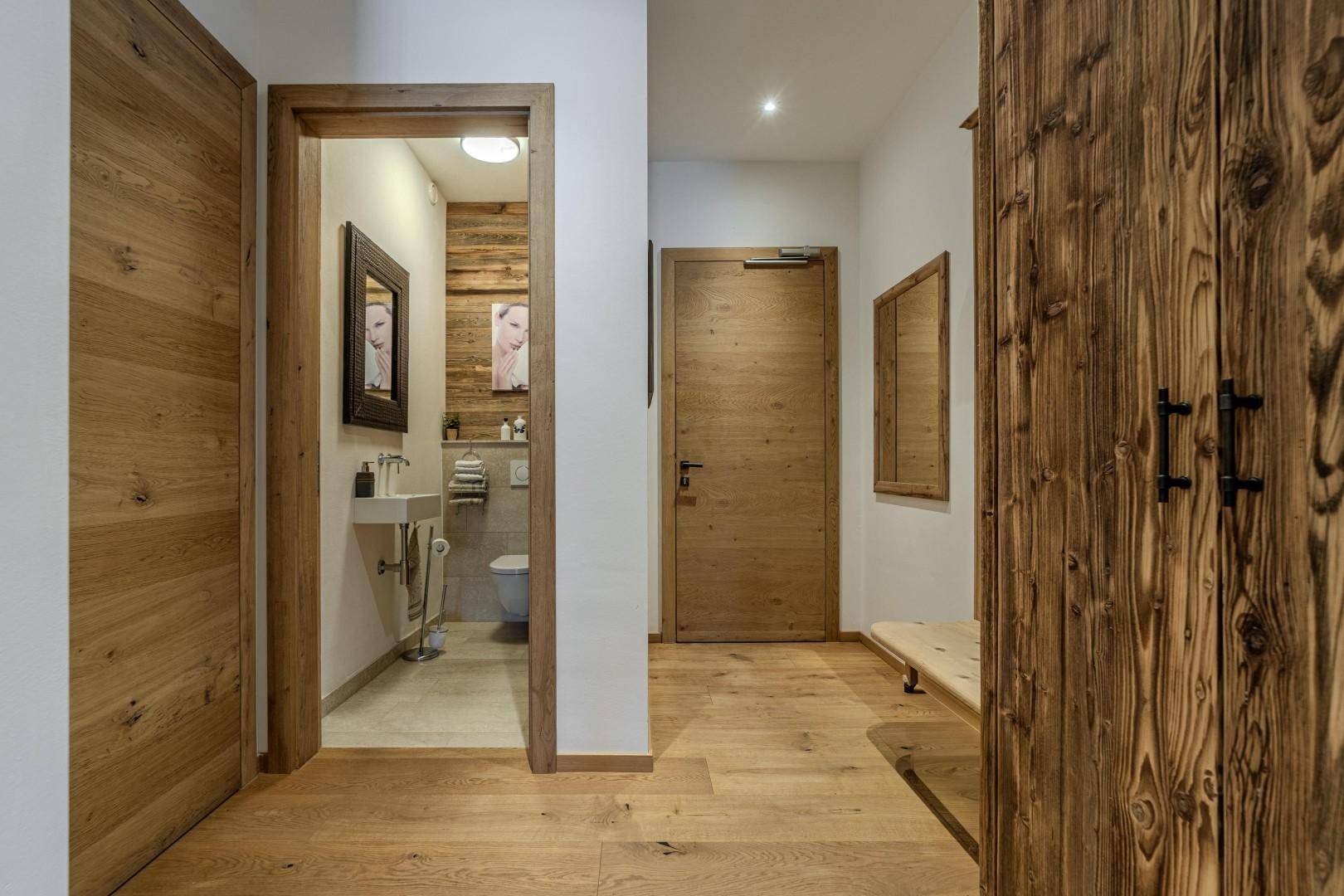 Flur mit Holzboden und Zugang zu einem Gäste-WC mit Holzverkleidung.