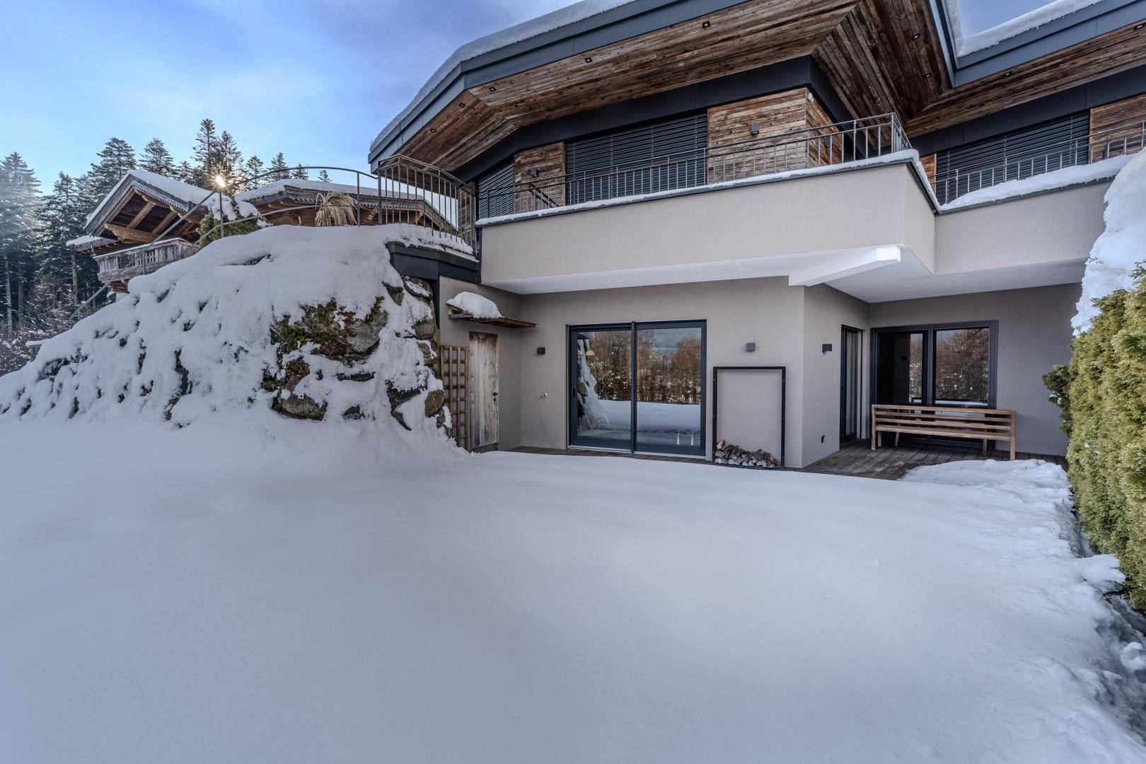 Rückansicht des Hauses mit großen Fenstern und Balkonen, umgeben von Schnee.