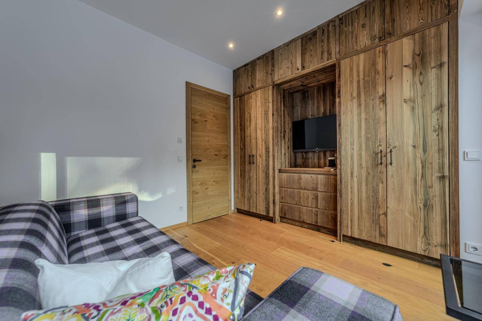 Schlafzimmer mit integriertem Fernseher in den Holzeinbauschränken und Holzboden.