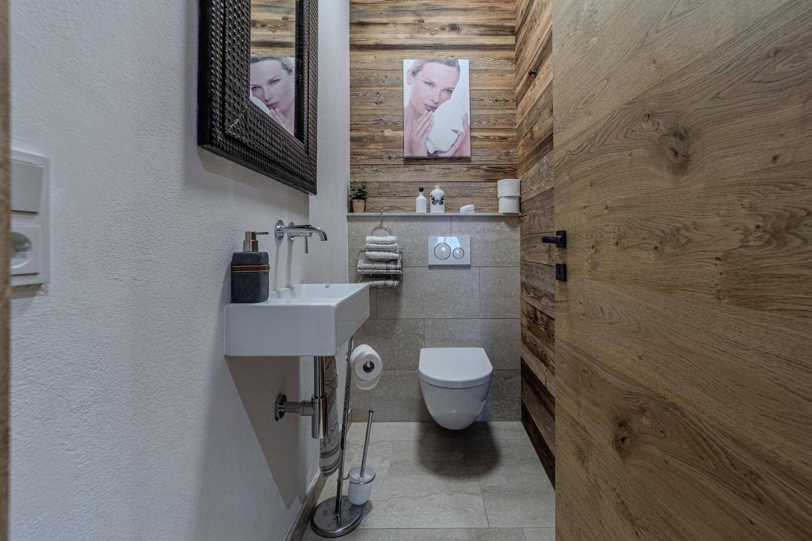 Modernes Gäste-WC mit Wand-WC, kleinem Waschbecken und Holzverkleidung an der Wand.