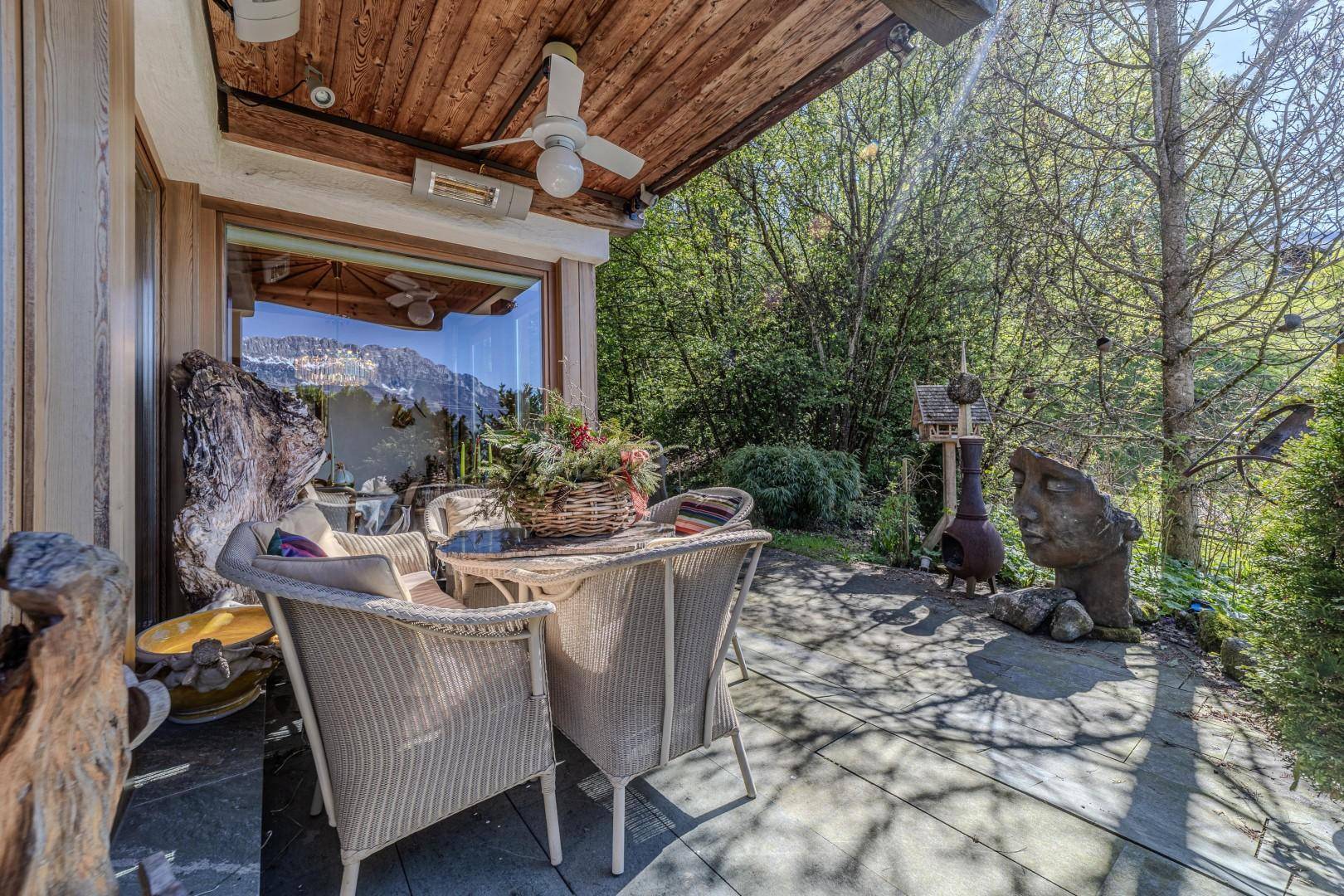Gemütliche Terrasse mit Korbmöbeln, Deckenventilator und Blick ins Grüne.