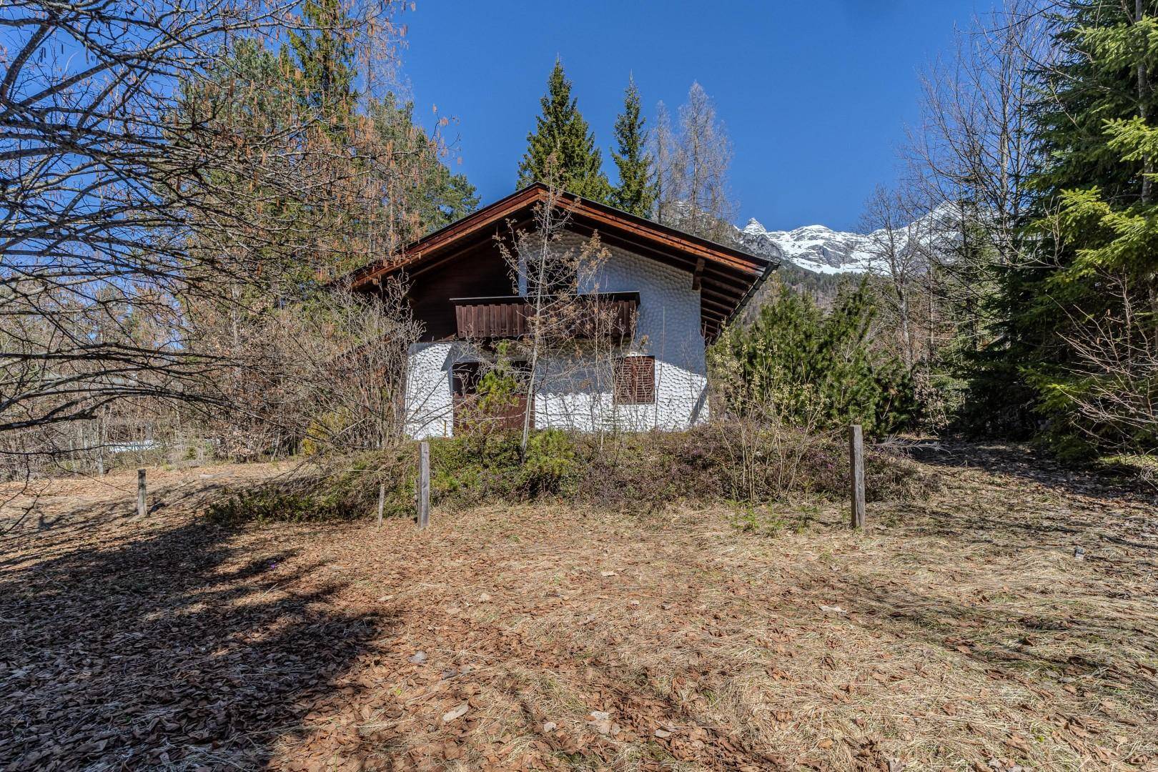Haus in idyllischer Naturkulisse mit schneebedeckten Bergen im Hintergrund.