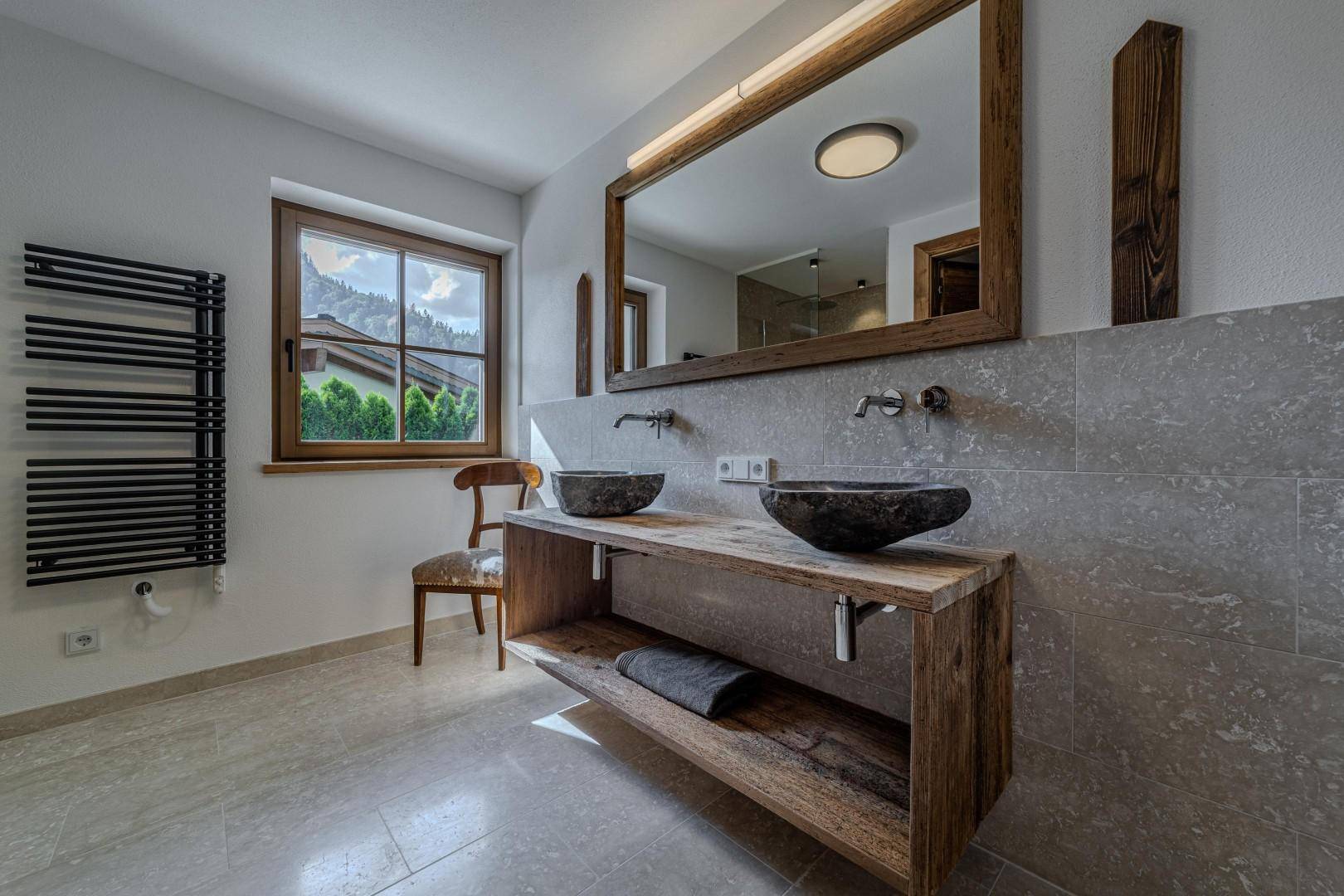 Modernes Badezimmer mit Doppelwaschbecken, Holzunterschrank und Fenster mit Bergblick.