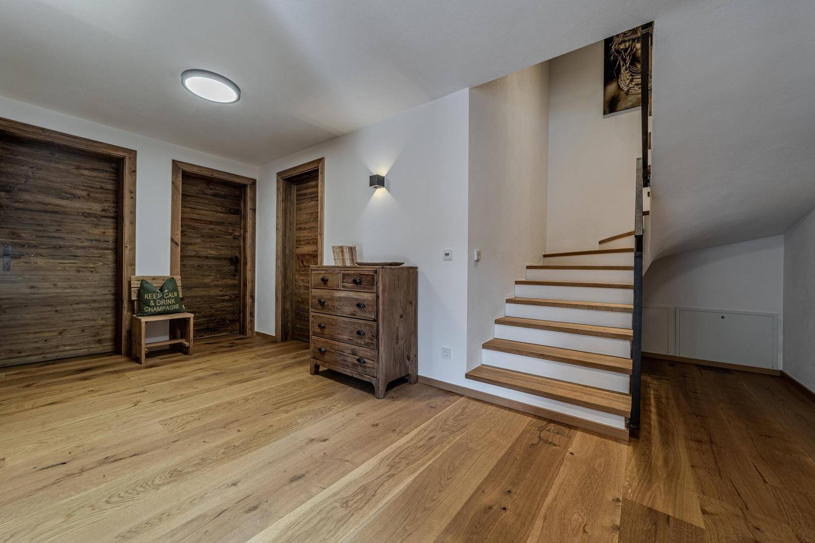 Heller Flur mit Holztreppe, Holzboden und rustikalen Holzmöbeln.