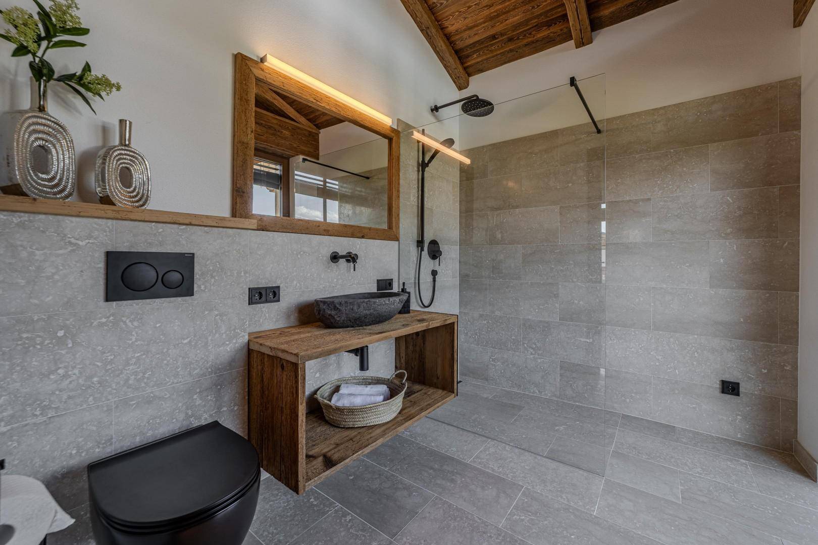 Modernes Badezimmer mit begehbarer Dusche, Steinwaschbecken und Holzelementen.